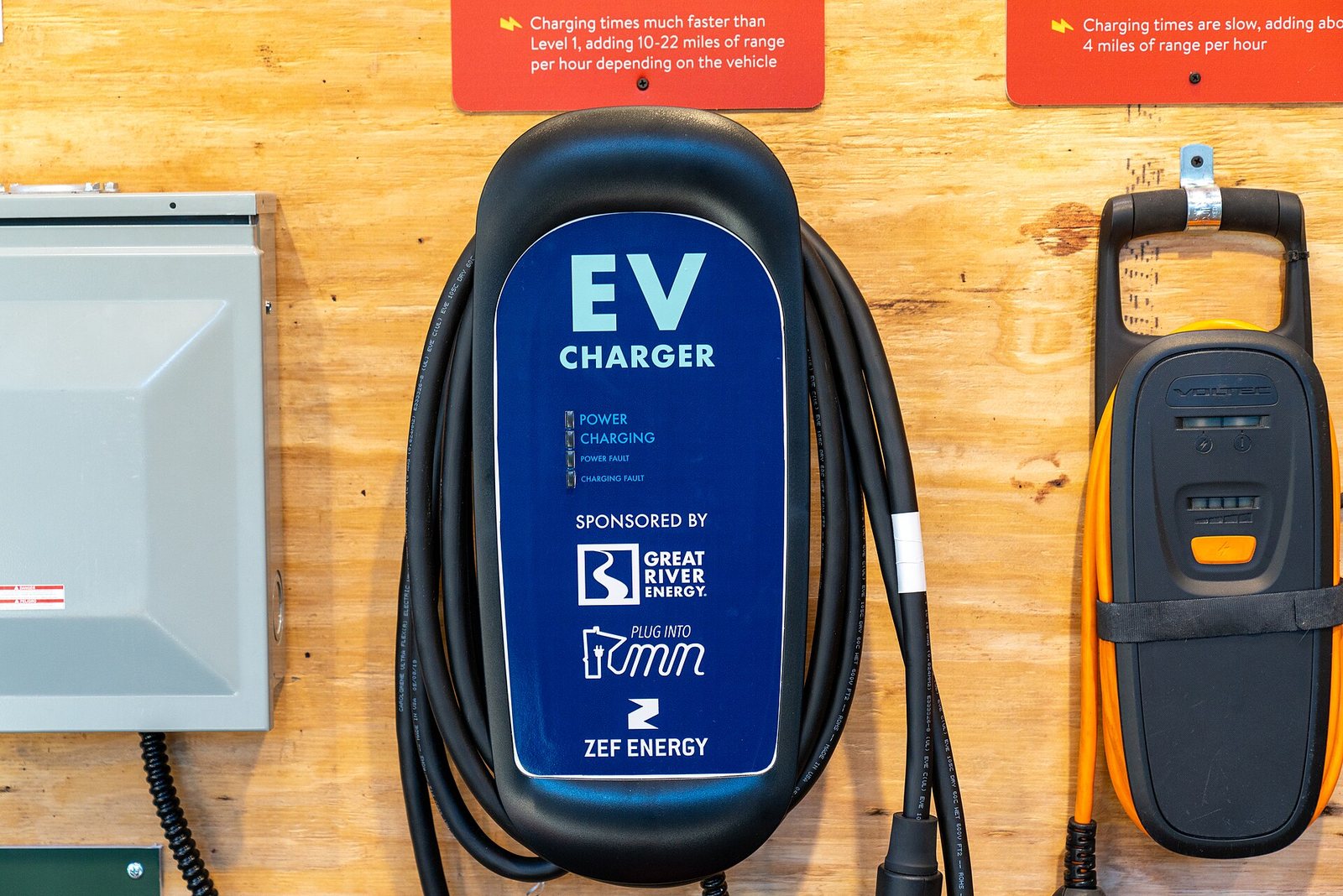 Outdoor blue pedestal Level 2 EV charging station beside a green painted electric vehicle parking stall
